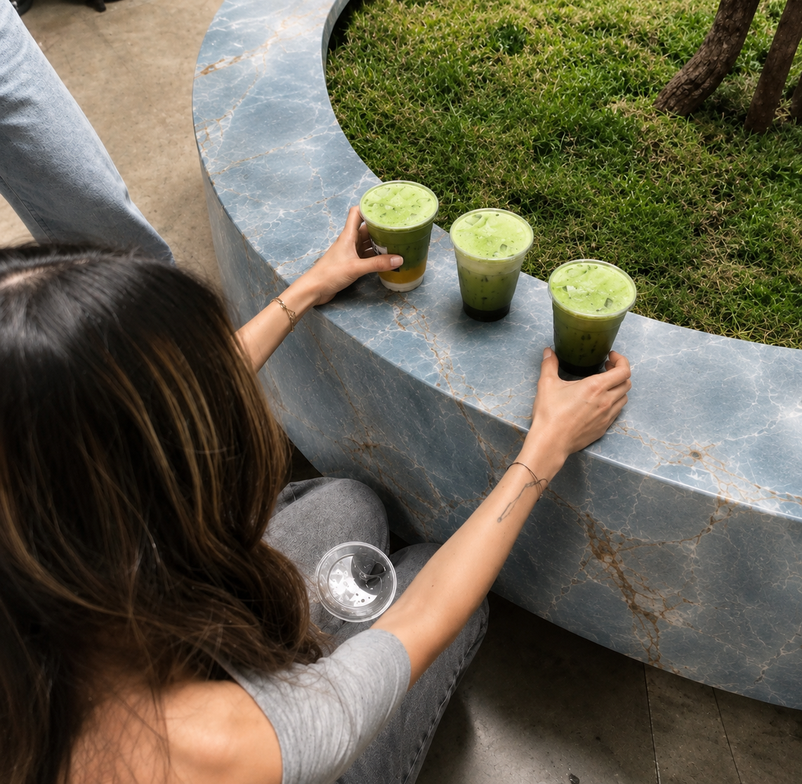 Three iced matcha drinks on a curved blue stone ledge