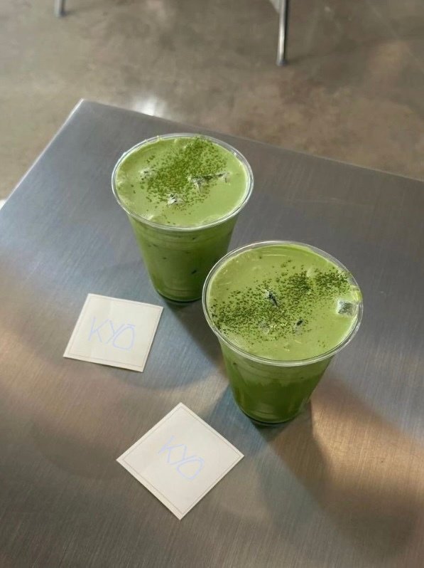 Two iced matcha lattes on a stainless counter